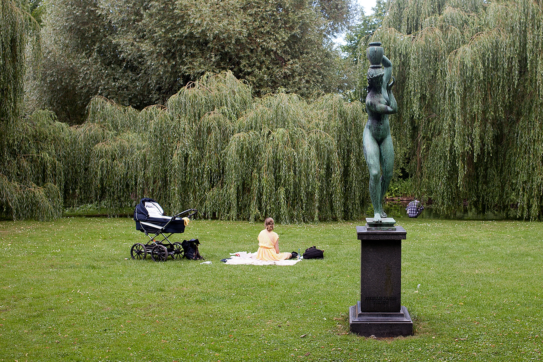 Figur und sitzende Frau im Park