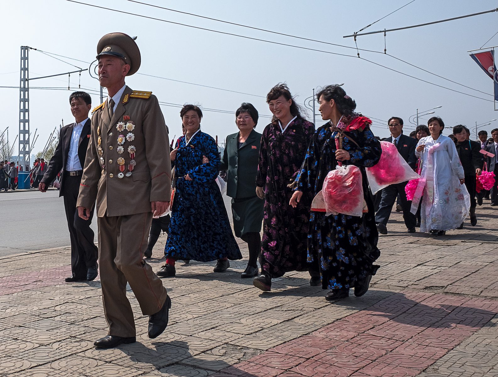 Vorübergehende Menschen mit roten Puscheln in der Hand in Pjöngjang, Nordkorea
