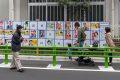 Menschen betrachten Wahlplakate bei bei den Einheitlichen Regionalwahlen in Tokio, Japan, 2019