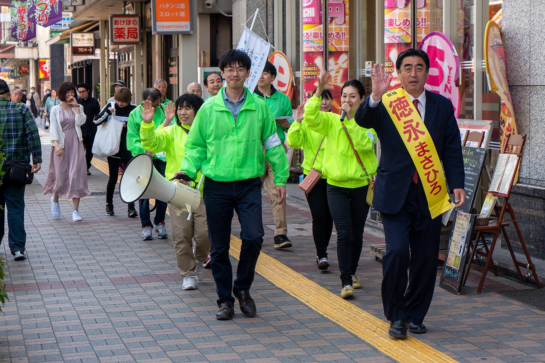 Ein Kanditat der DDP mit Wahltrupp im Beitrag Tokio: Einheitliche Wahl