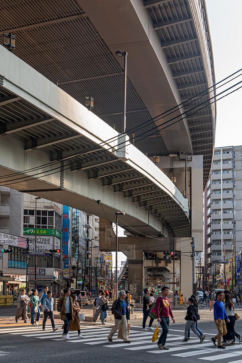 Fußgänger auf Zebrastreifen unter einer Autostraße in Tokyo