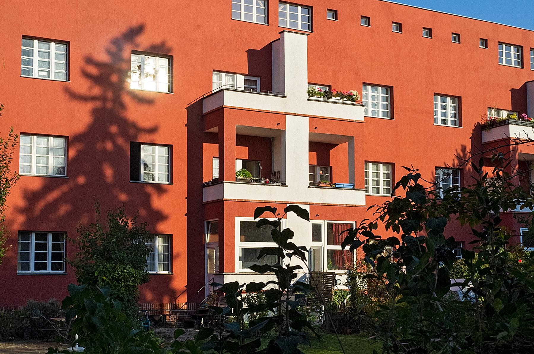 Rote Hausfassade mit weißen Balkonen im Beitrag Berlin: Hufeisen Siedlung
