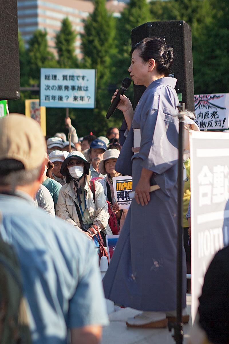 Eine Frau in traditioneller Kleidung hält eine Rede auf der Seite Stadterkundung.com