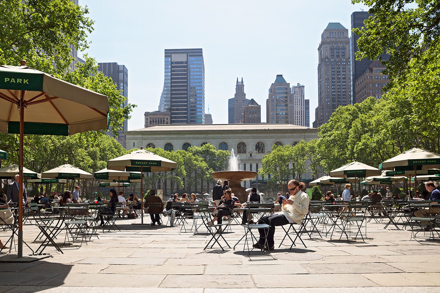 Menschen, die an Tischen sitzen im Bryant Park, Manhattan auf der Seite Stadterkundung.com