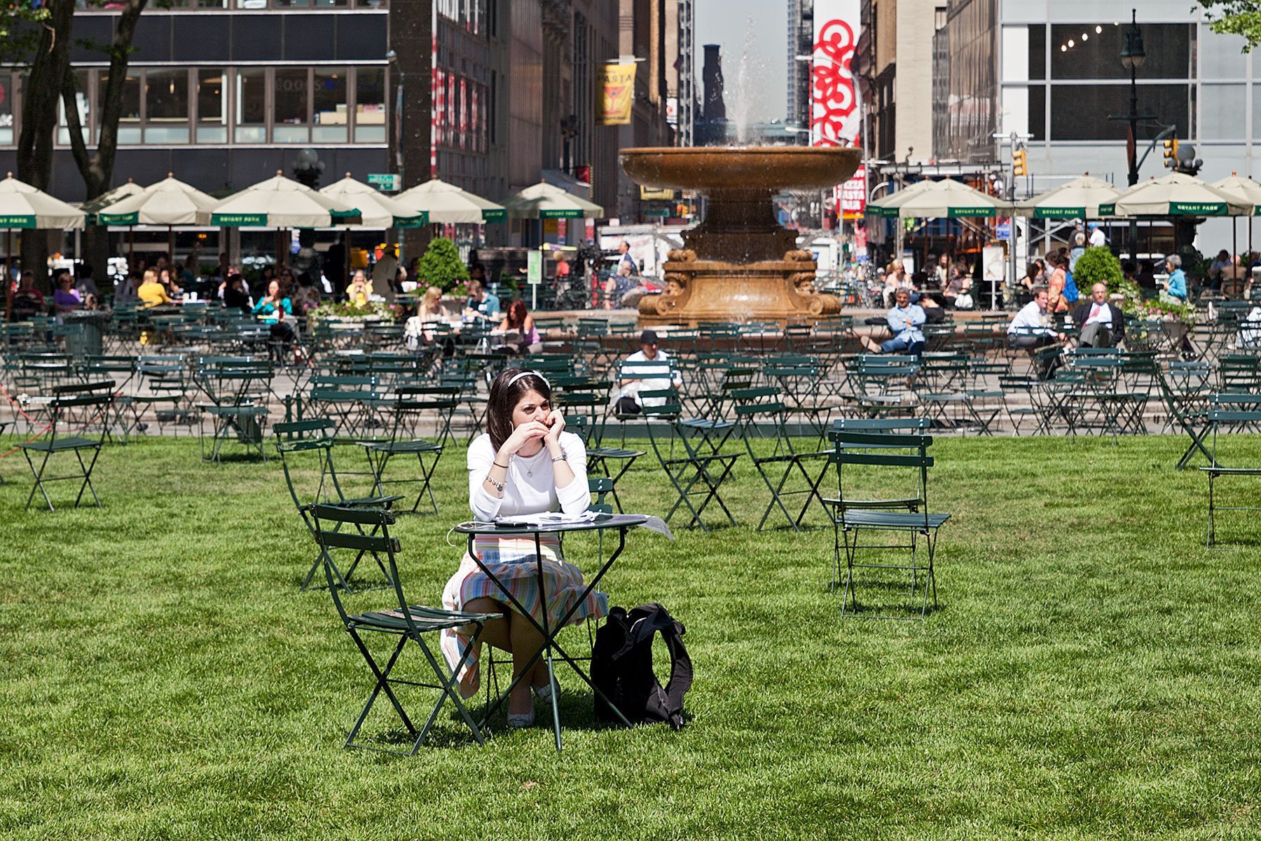 Eine Frau sitzt am Tisch im Bryant Park, Manhattan auf der Seite Stadterkundung.com